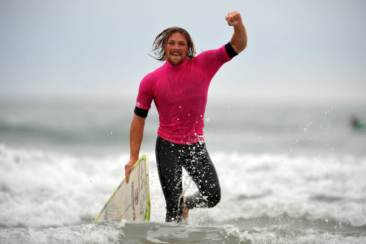 Man comes out of sea with a surf board