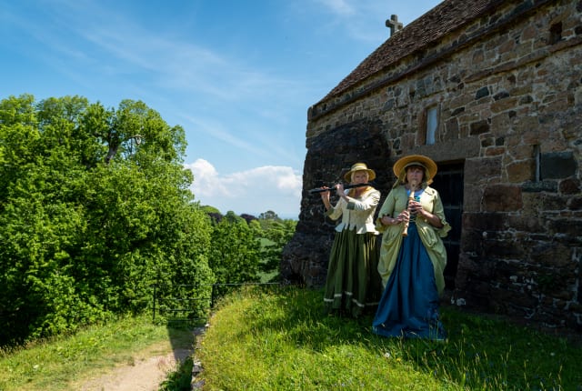 Two musicians in a field next to a Chapel