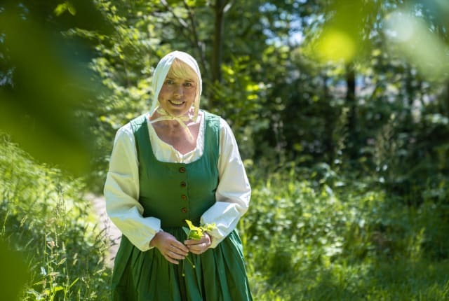 Woman in green costume walks in a field