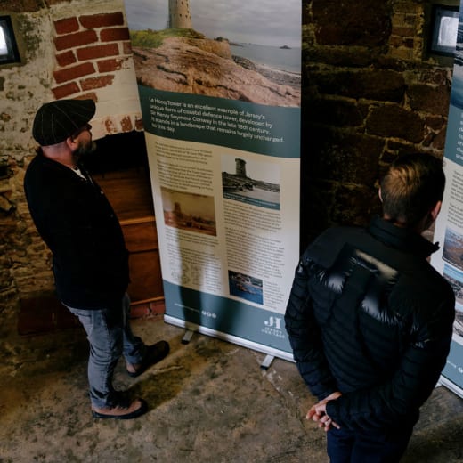 Two men read an exhibition in a stone building