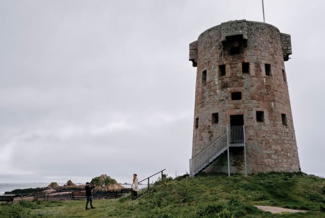Couple take photo of large round tower with a flag flying