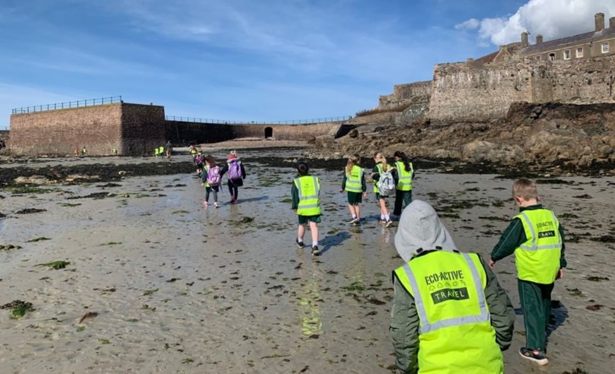 Children in high vis vests visit a castle