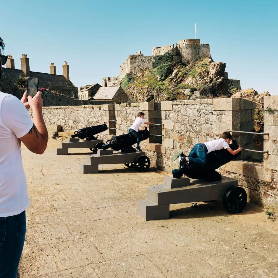 Elizabeth Castle man takes picture of sons sitting on cannons with Castle in background