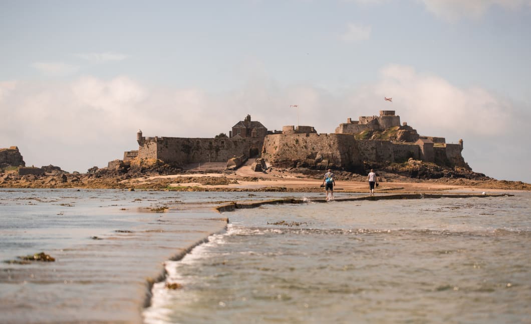 a castle with a walkway through an incoming tide