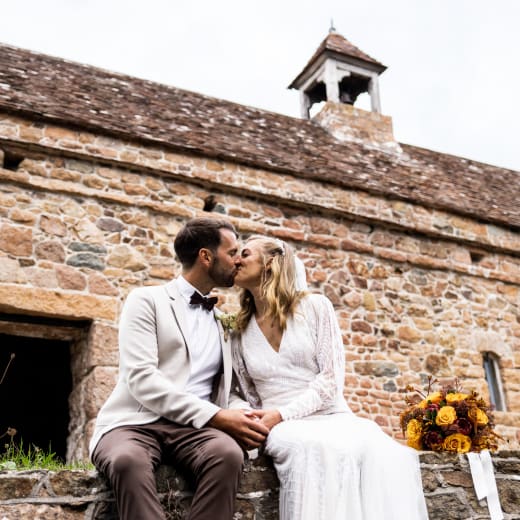 La Hougue Bie Bride and Groom kiss with Chaple in Background