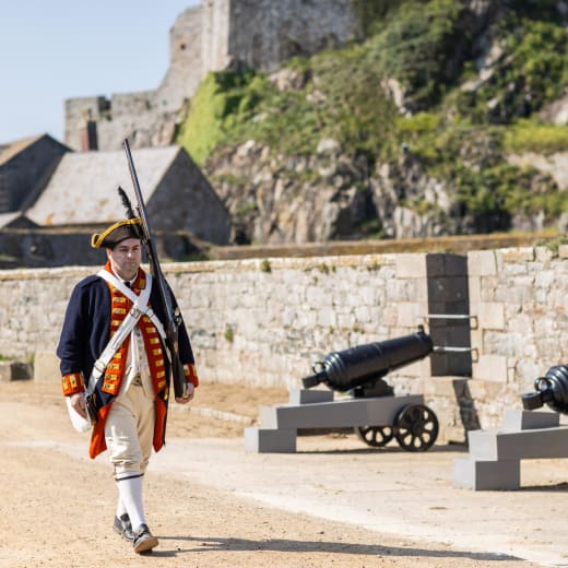 Person in Militia costume walks by cannons
