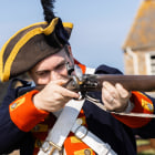 Person in Militia costume aims a gun