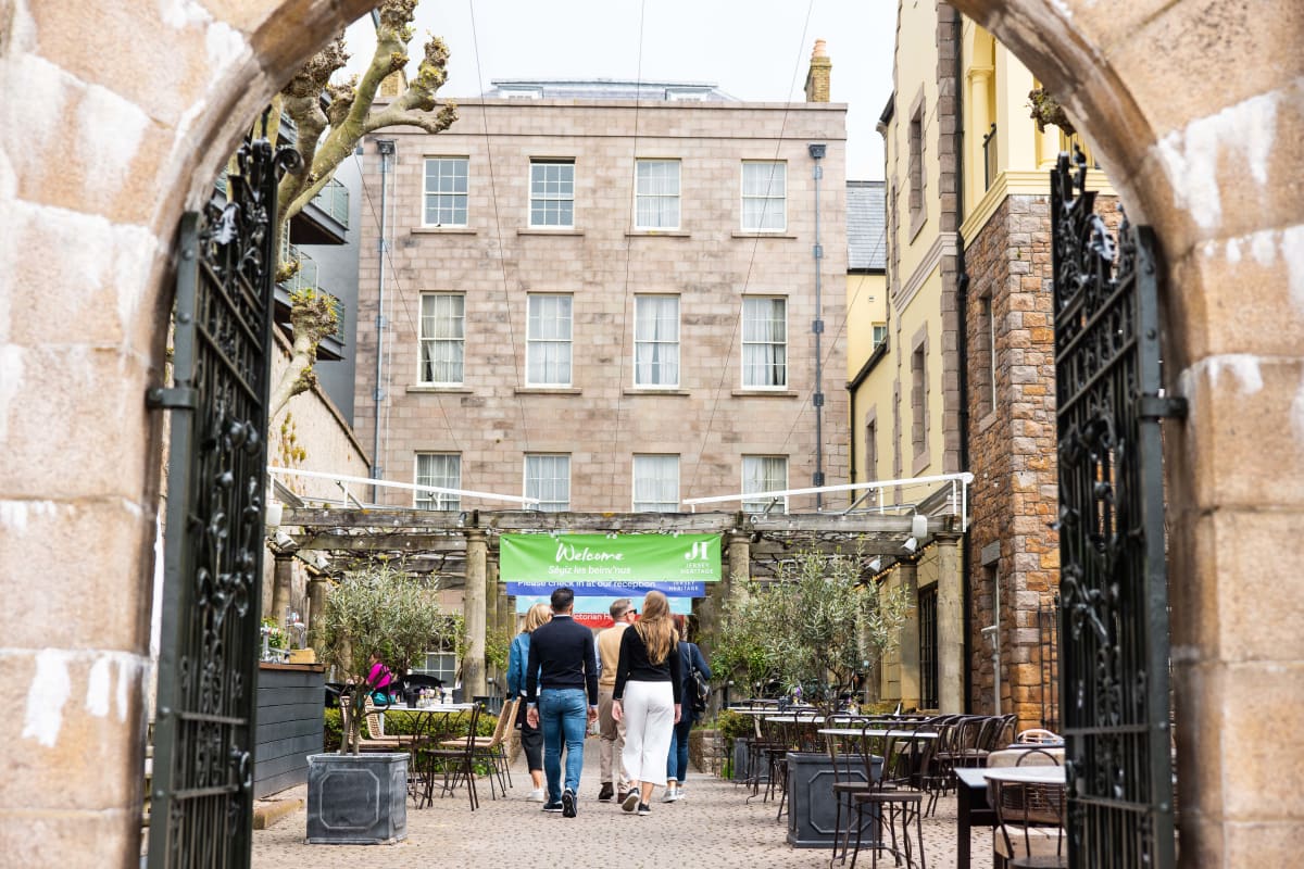 group of people walk towards a building through large gates