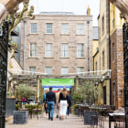 group of people walk towards a building through large gates