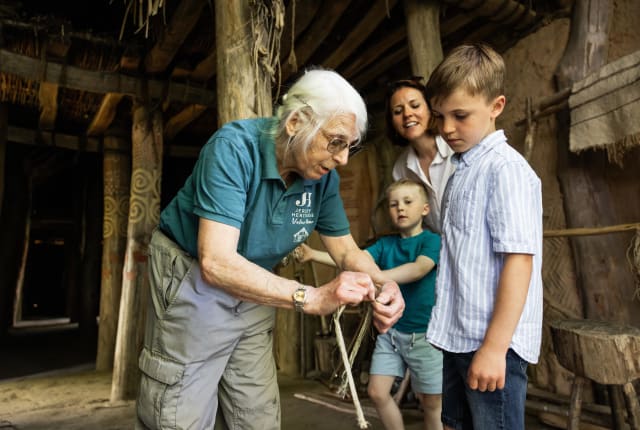 Person shows a young boy how to tie a knot