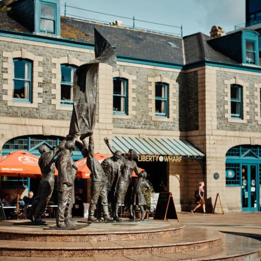 Buildings with a statue in front and cafe awnings