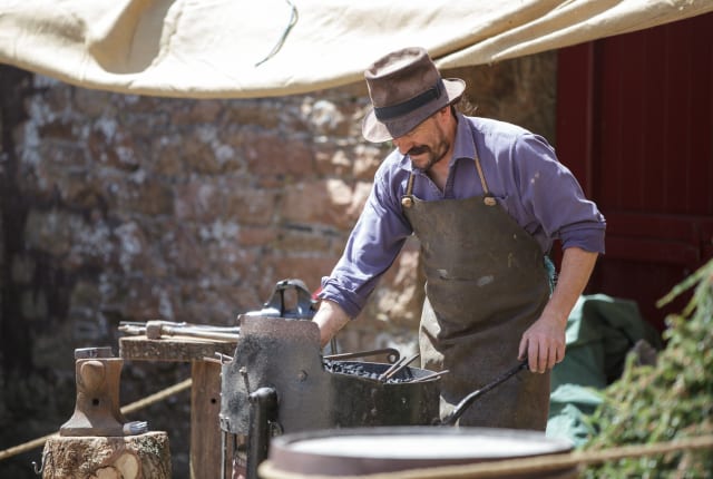 Man in hat works at a forge