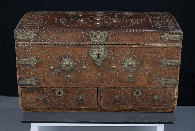 a wooden travel chest with ornate brass fastenings and pattern