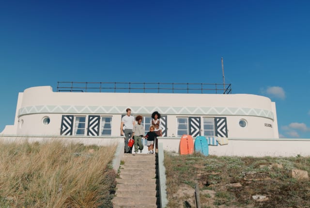 Family with surf boards sit at the top of some steps