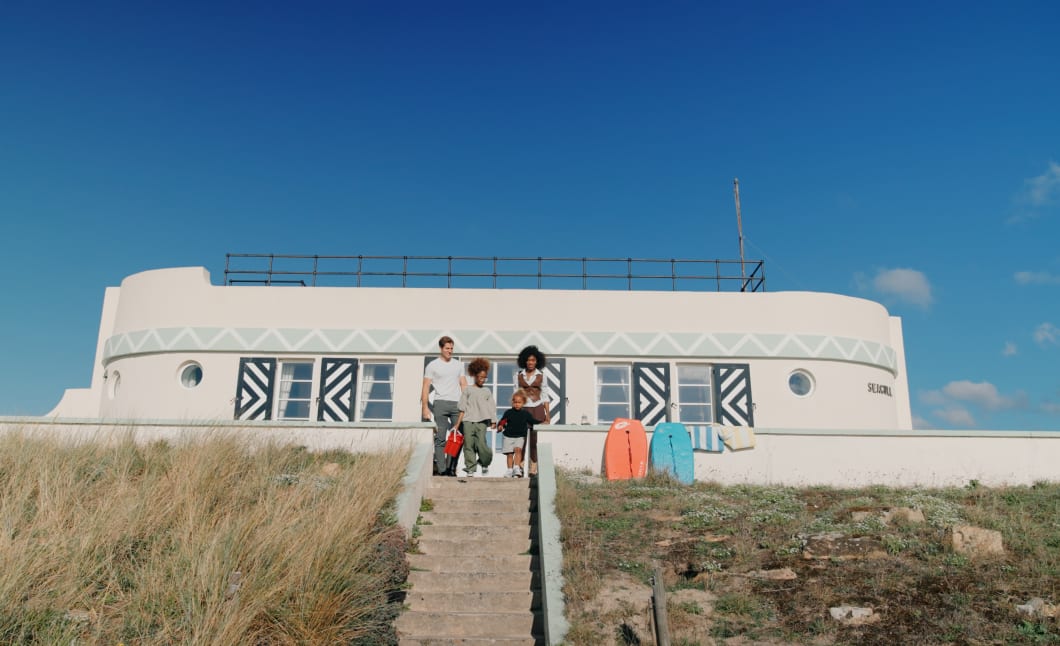 Family with surf boards sit at the top of some steps