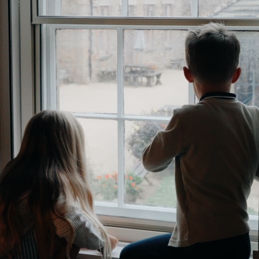Two children look out of a window.