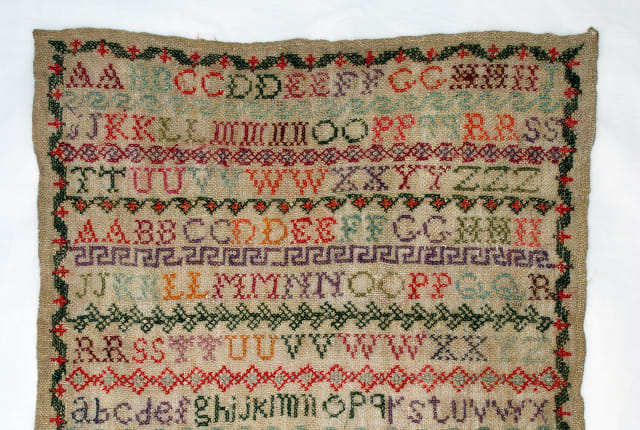 A sampler showing a colourful alpabet
